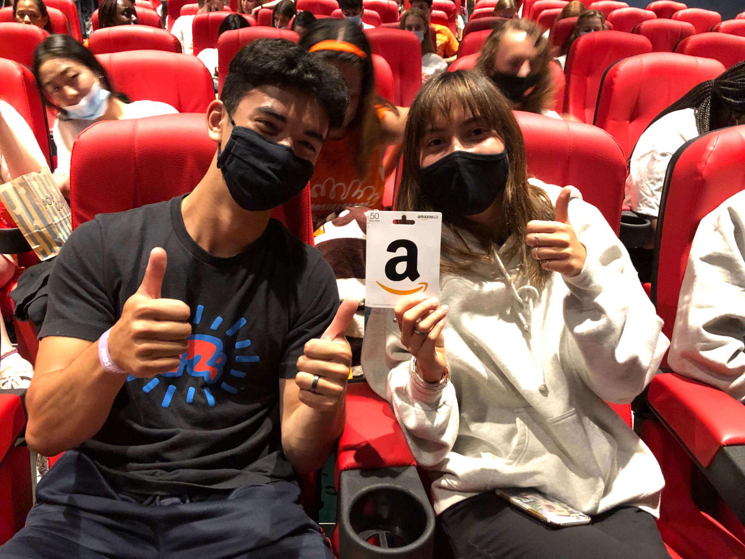 Two students sitting in a movie theatre with an Amazon gift card