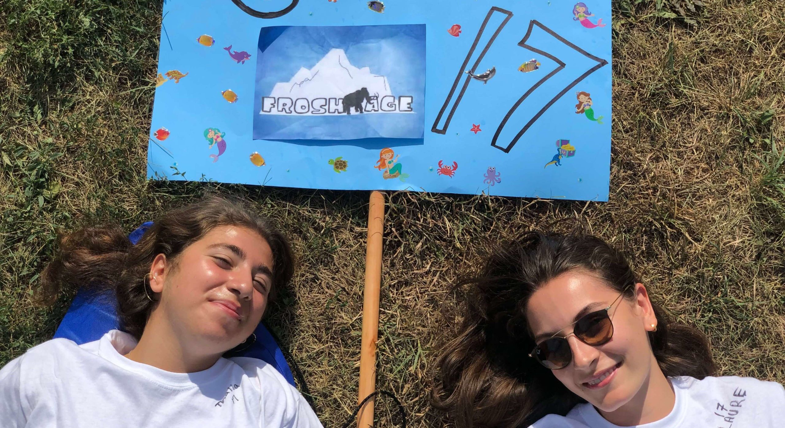Students laying in grass with Frosh sign