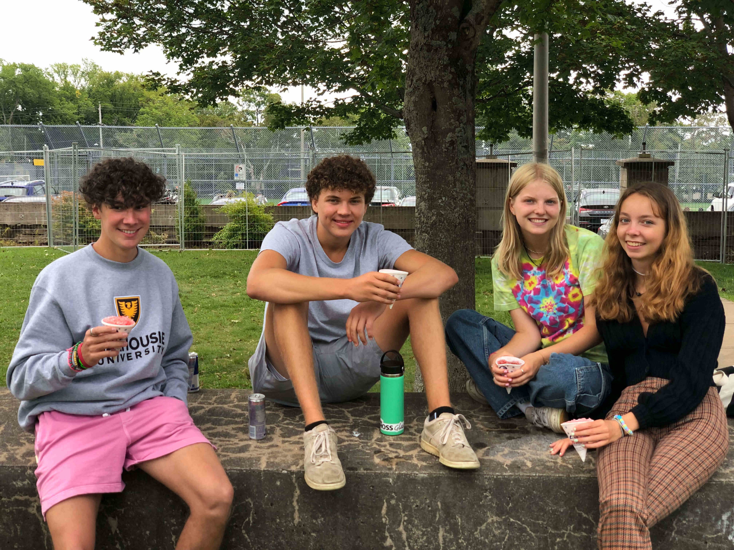 4 students sitting on bench at Carnival Day